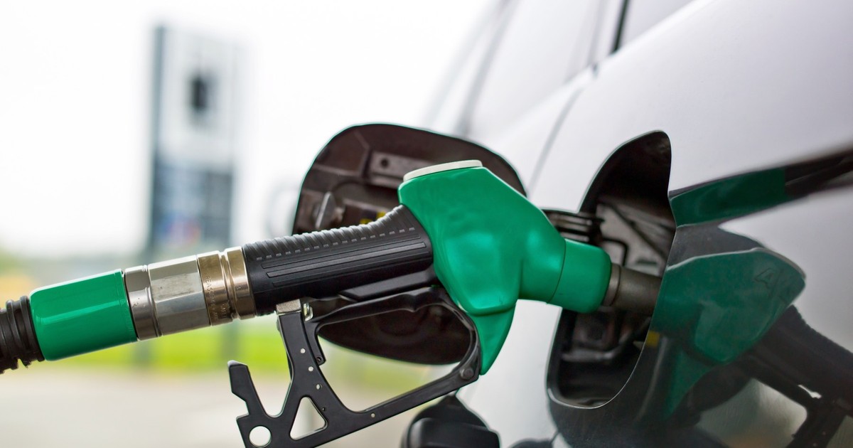 O pompă verde alimentează un automobil de culoare neagră.