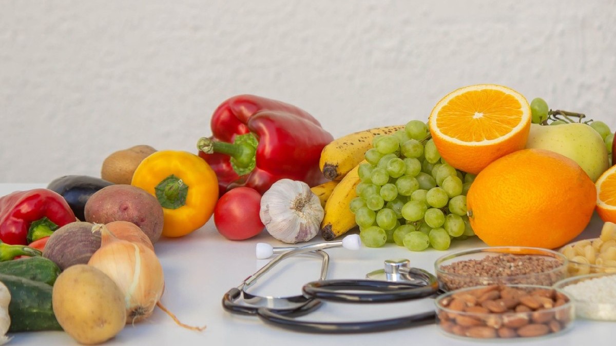 Alimentație sănătoasă și medicamente: un stetoscop printre fructe, legume și cereale.