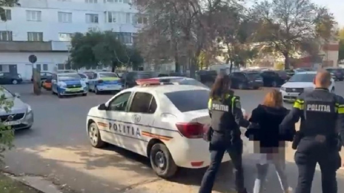 O tânără escortată de doi polițiști, în imagine se vede și o mașină de Poliție - octombrie 2025