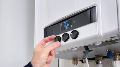 Cum să pregăteşti centrala termică pentru sezonul rece - Prim-plan al mâinii unui bărbat care se schimbă temperatura la centrala termică