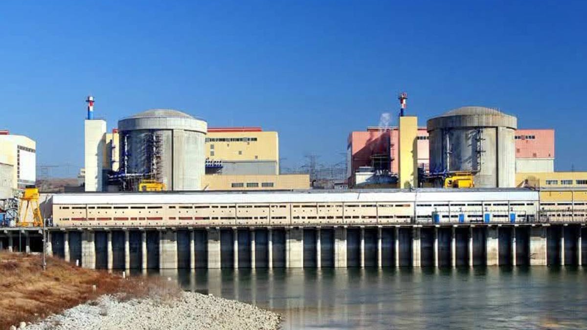 Centrala nucleară de la Cernavodă, văzută din exterior. În imagine apar clădirile celor două reactoare, amplasate lângă apă, sub un cer senin.