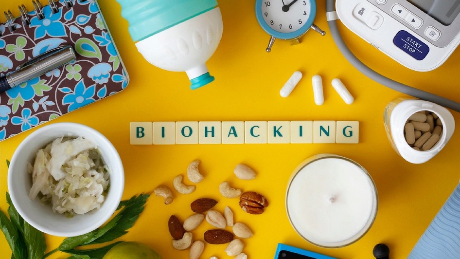 textul „Biohacking” pe fundal galben, înconjurat de diverse obiecte ce fac parte dintr-un stil de viață sănătos 