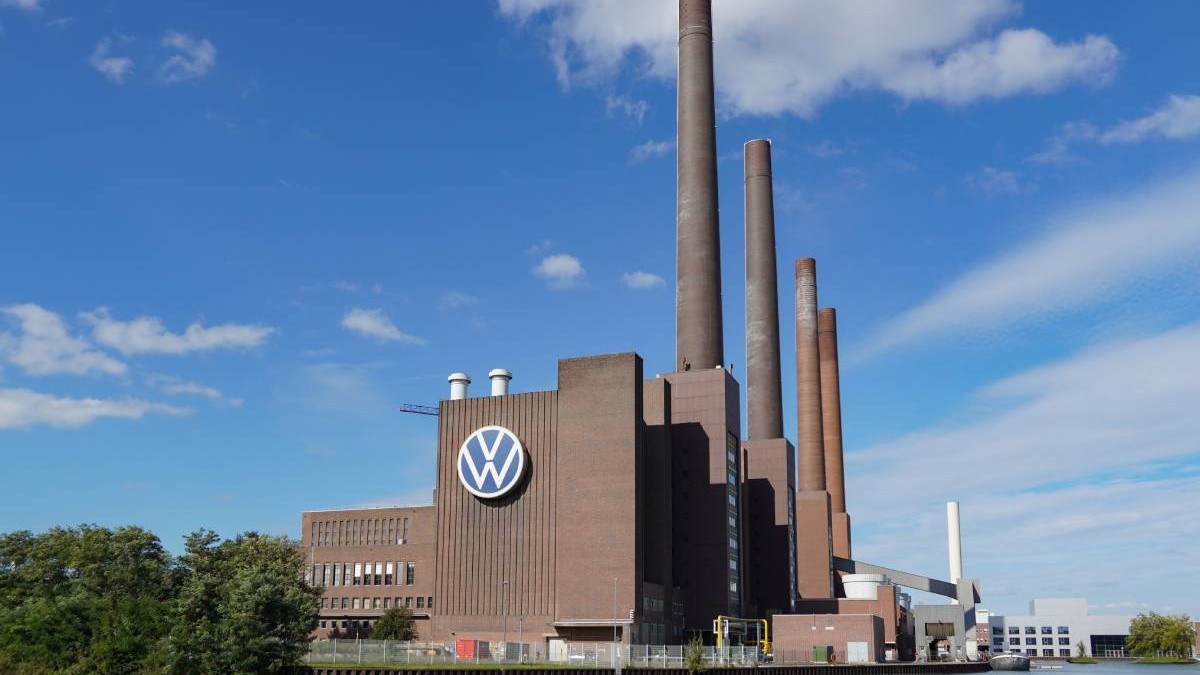fabrica de producție a sediului Volkswagen din Wolfsburg cu docul și canalul în prim plan și logo-ul mare Volkswagen pe fațada fabricii
