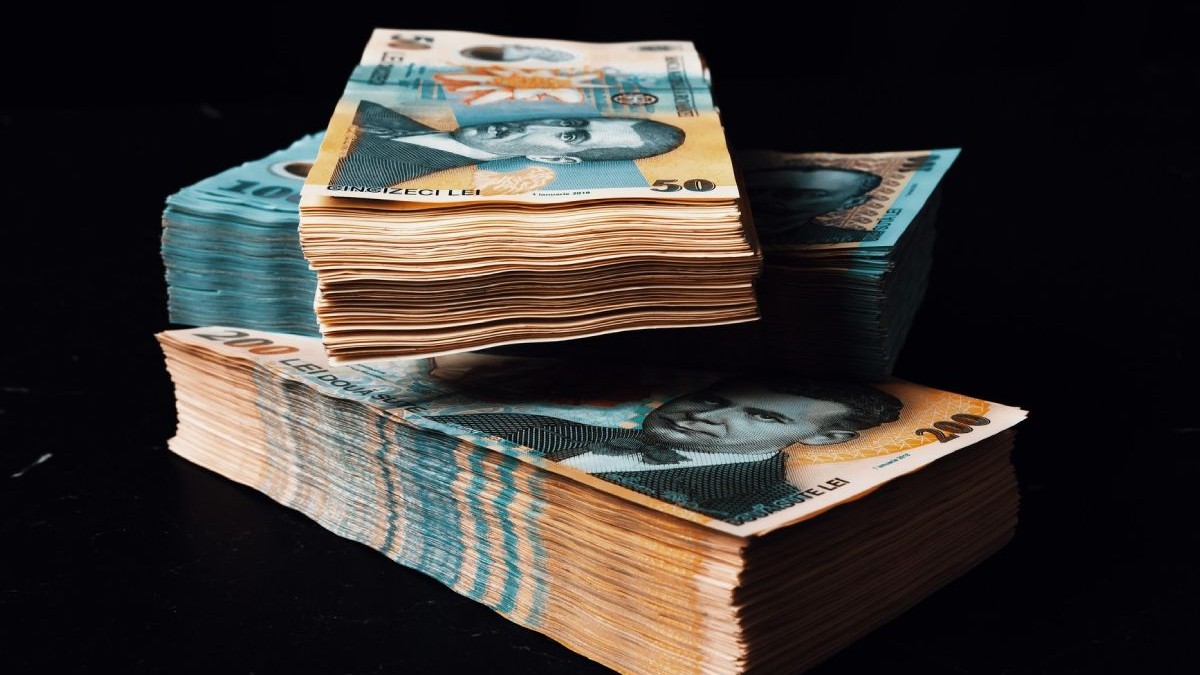 Trei teancuri de bancnote de 100 și 200 de lei pe fundal negru