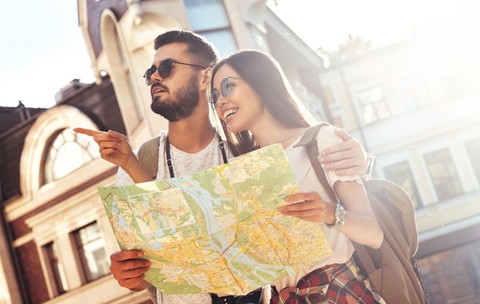 Un cuplu fericit care explorează străzile orașului cu ajutorul unei hărți