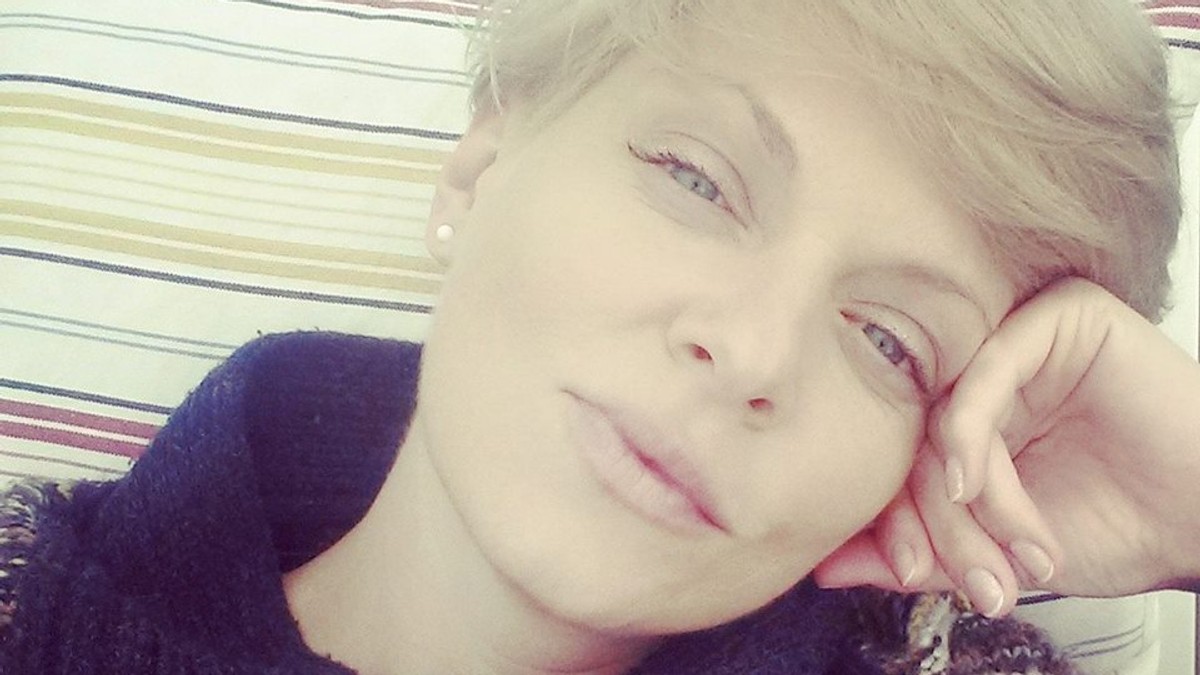 Dana Nălbaru stă pe canapea, cu o mână la frunte, gânditoare
