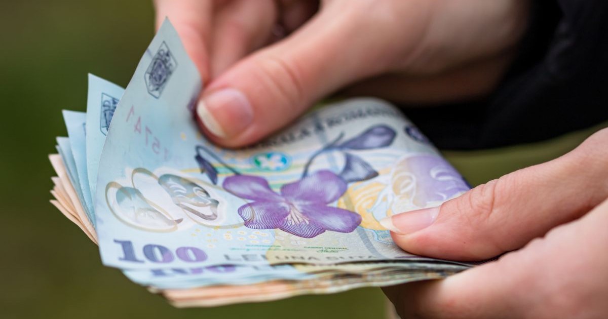 o mână de femeie numara bani românesti, lei, bancnote de 100 de lei