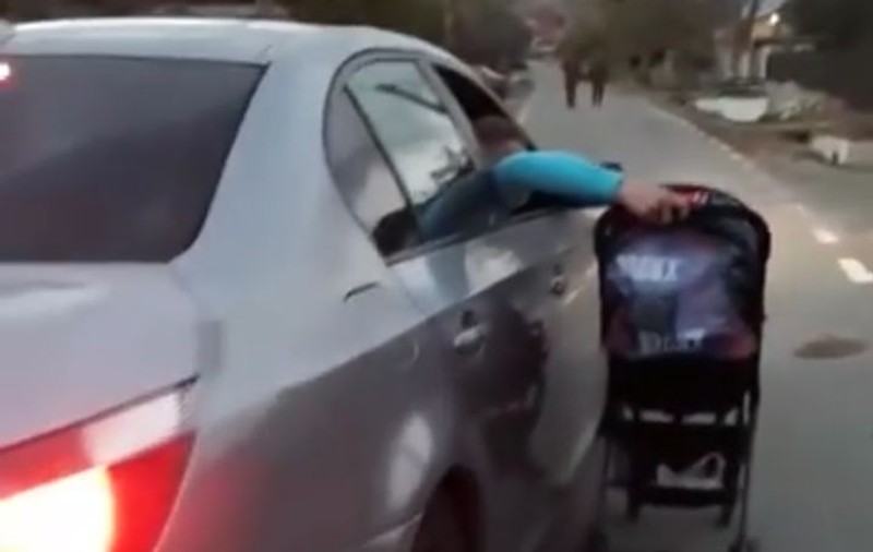 FOTO | Imagini șocante în Gorj. Un bebeluș a fost plimbat de tatăl lui pe lângă maşină, în mers