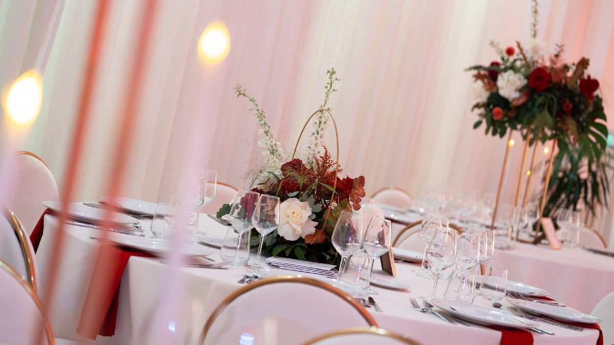 Interior de restaurant pregătit pentru o nuntă, cu aranjamente florale sofisticate și decorațiuni