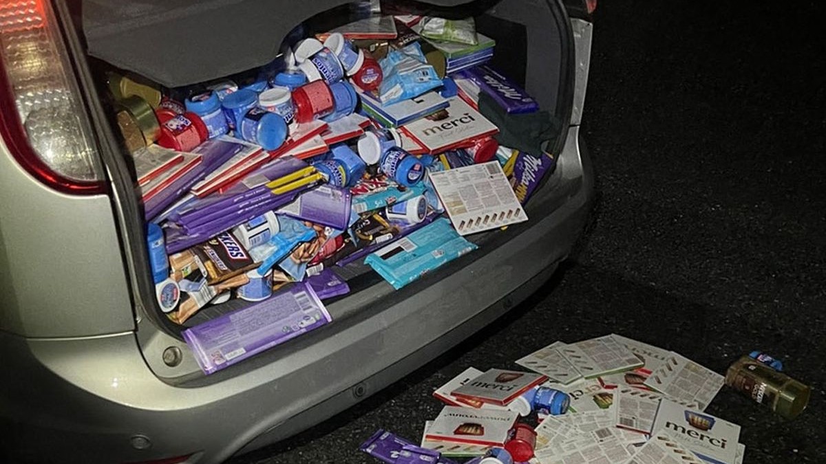 Portbagajul unei mașini este deschis și plin de dulciuri, printre care se văd ciocolată Milka și Merci, Snickers și cutii cu gume de mestecat, Olanda, 23 octombrie 2025