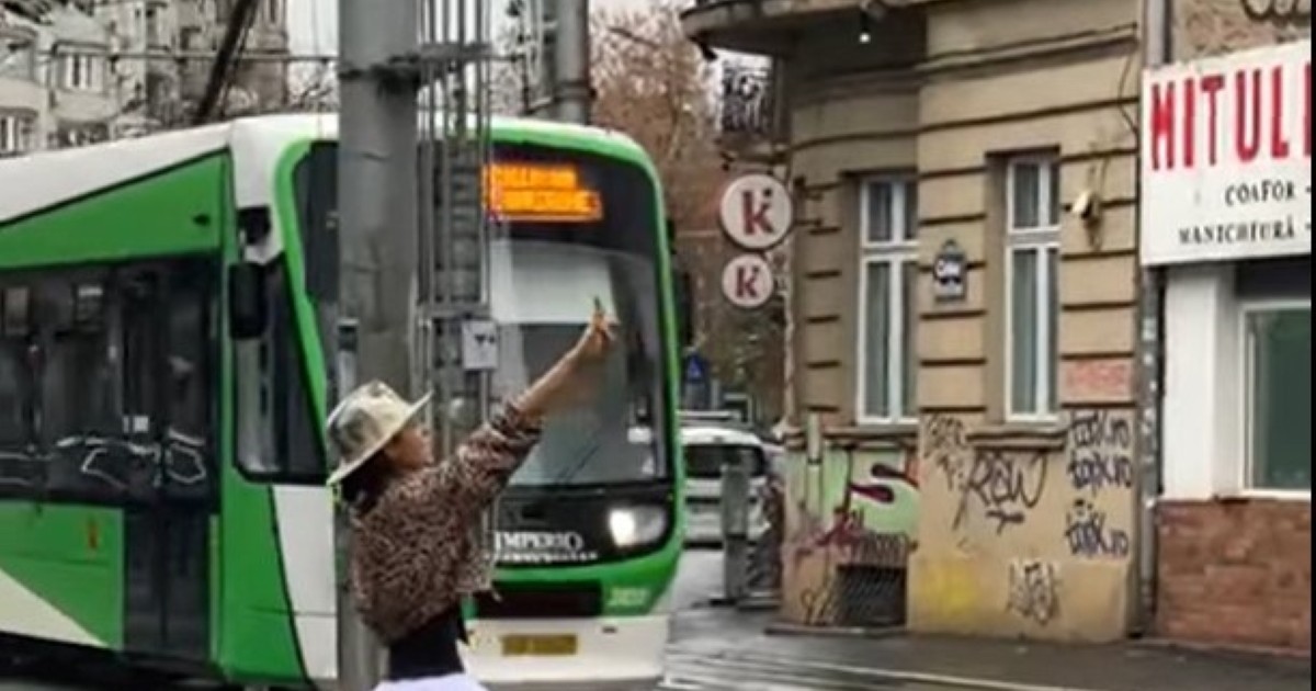 femeie in tutu rox dansand pe strazile bucurestiului cu un tramvai care trece prin spatele ei