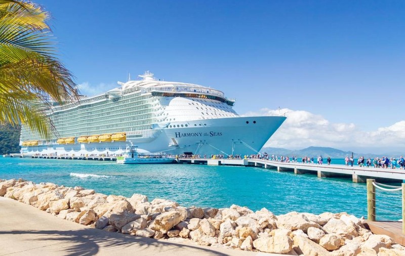 Un vas de croazieră ancorat în port, iar turiștii coboară pentru a vizita insula