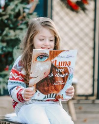 Sara, fiica Andreei Lițescu, răsfoiește cartea „Luna vrea să zboare”