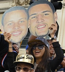 epa04808927 A woman holds up pictures of Golden State Warriors players Stephen Curry (L) and Klay Thompson (R) while crowds line up waiting for the Golden State Warriors 2015 NBA Championship Parade and Rally in downtown Oakland, California, USA, 19 June 2015. The Warriors defeated the Cleveland Cavaliers in the NBA Finals. EPA/JOHN G. MABANGLO