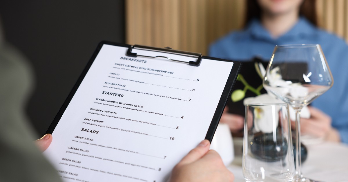 Doi oameni care stau la masă la restaurant și citesc meniul