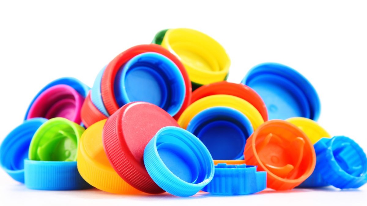 Capace colorate din plastic, de la sticle, simbolizând reciclarea sticlelor, pe fundal alb.