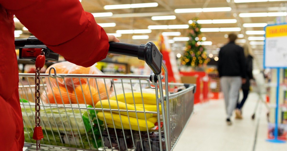 Program magazine de Crăciun 2022 - Imagine cu o femeie cu un cărucior în care îşi pune cumpărăturile de Crăciun, într-un supermarket