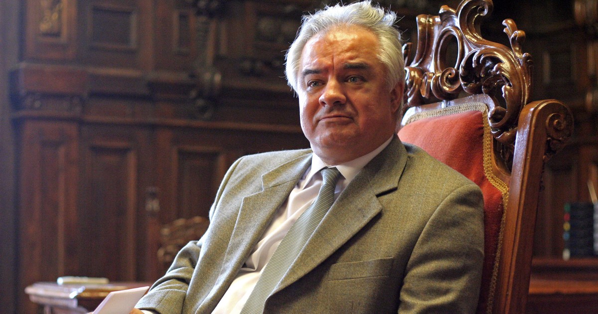 Avertisment de la BNR: Taxa pe tranzacții bancare este absurdă și a mai aplicat-o Venezuela. Când nu colectezi 9 miliarde de euro din TVA, este strigător la cer. Eugen Rădulescu, la costum, într-un scaun, la o masă de lemn masiv