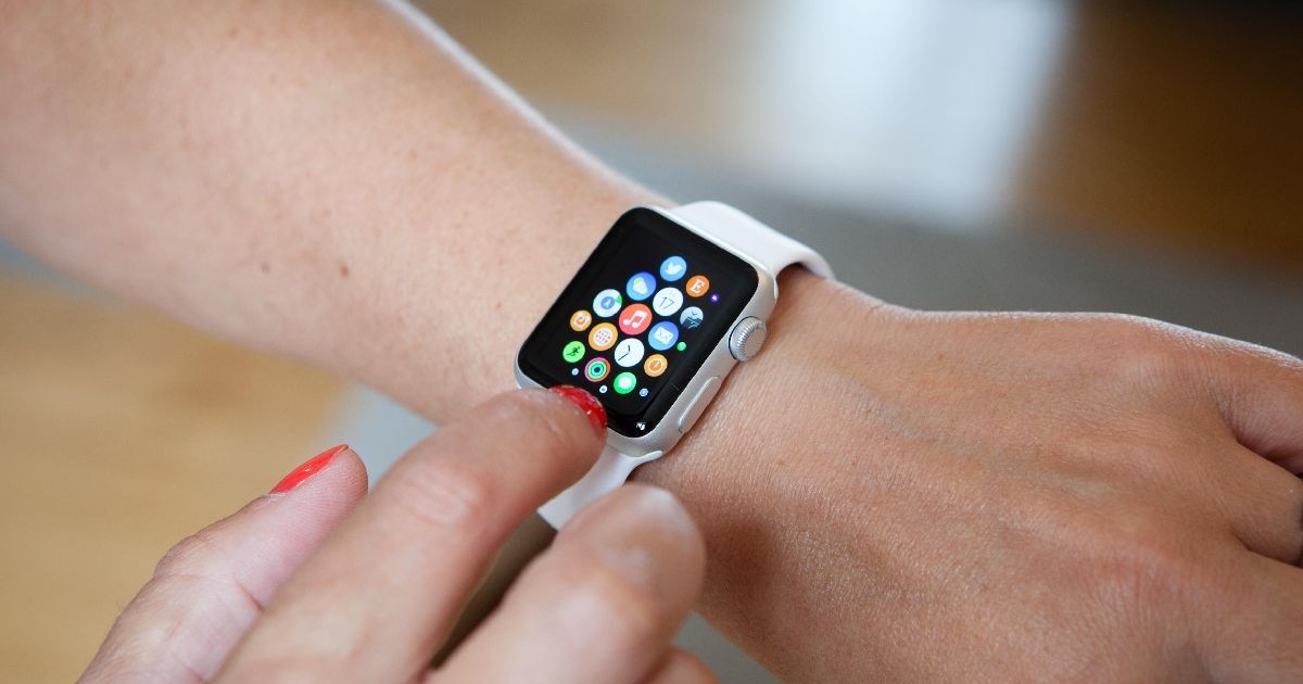 Un Apple Watch alb care arată ecranul de pornire, la încheietura unei femei.