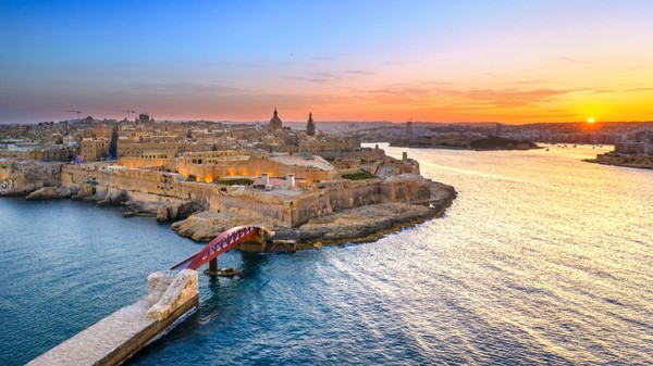 Imaginea prezintă o vedere aeriană asupra orașului istoric Valletta, capitala Maltei, văzută la apus de soare.