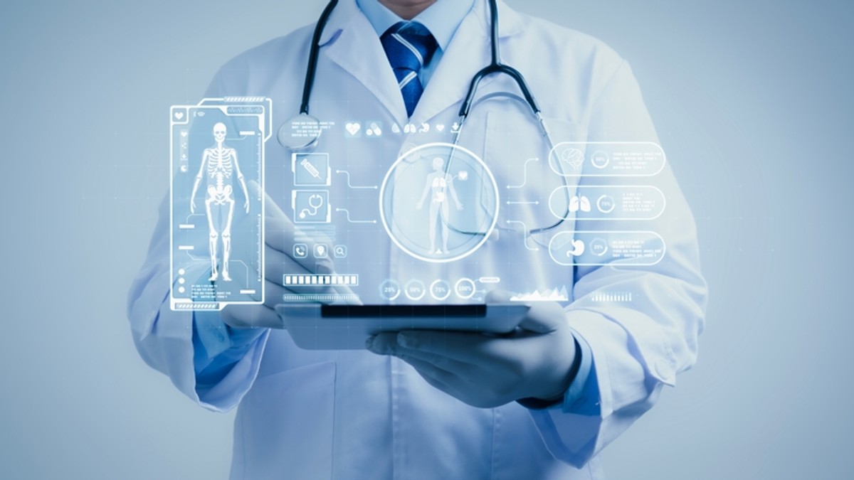 Câte organe sunt în corpul uman - Imagine cu un medic care ţine în mână o tabletă, desupra căreia este o imagine grafică reprezentând oase şi organe ale corpului uman.