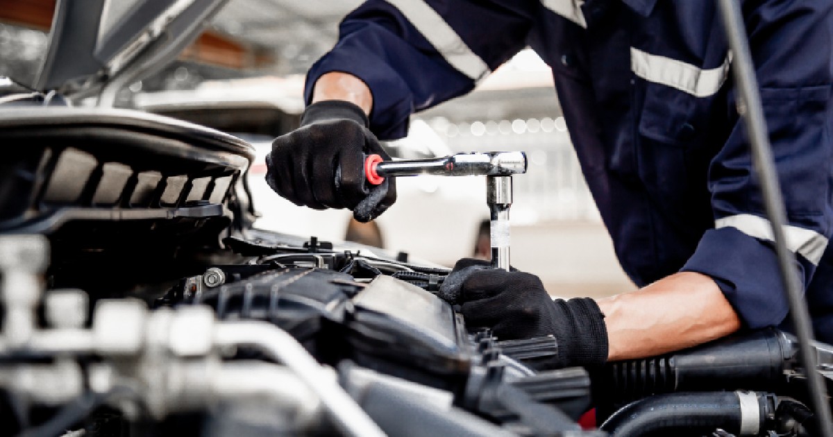 prim-plan cu un tehnician auto care utilizează o cheie pentru a repara și înlocui piese de schimb ale motorului unui autovehicul