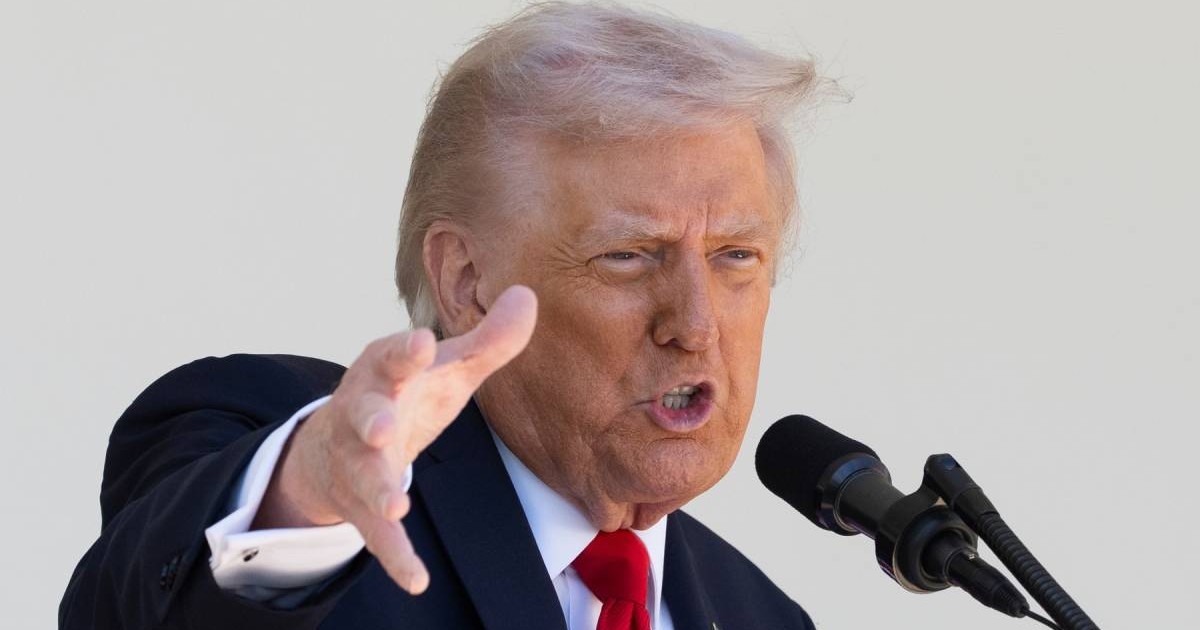 Donald Trump, președintele SUA, in sacou negru, camasă albă si cravata, rosie, cu mana dreapta ridicata si palma deschisa, orientata in fata, surprins in timp ce vorbeste la microfon
