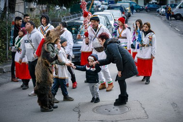 O femeie și nepoțelul ei s-au oprit să dea bani urătorilor