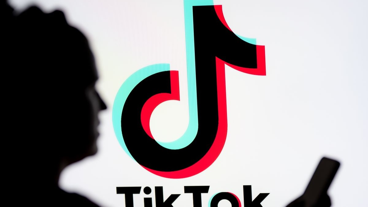 O femeie se uitâ pe un smartphone cu o siglă TikTok afișată în fundal