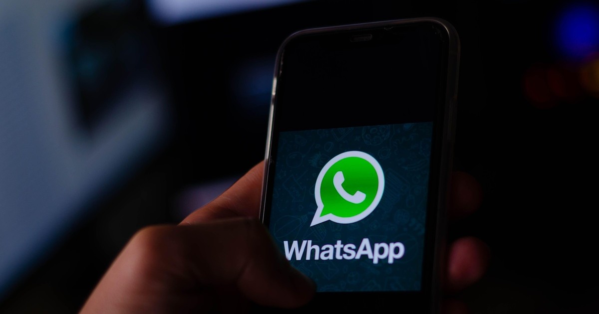 Persoană care ține în mâini un telefon mobil, iar pe ecran este logo-ul Whatsapp
