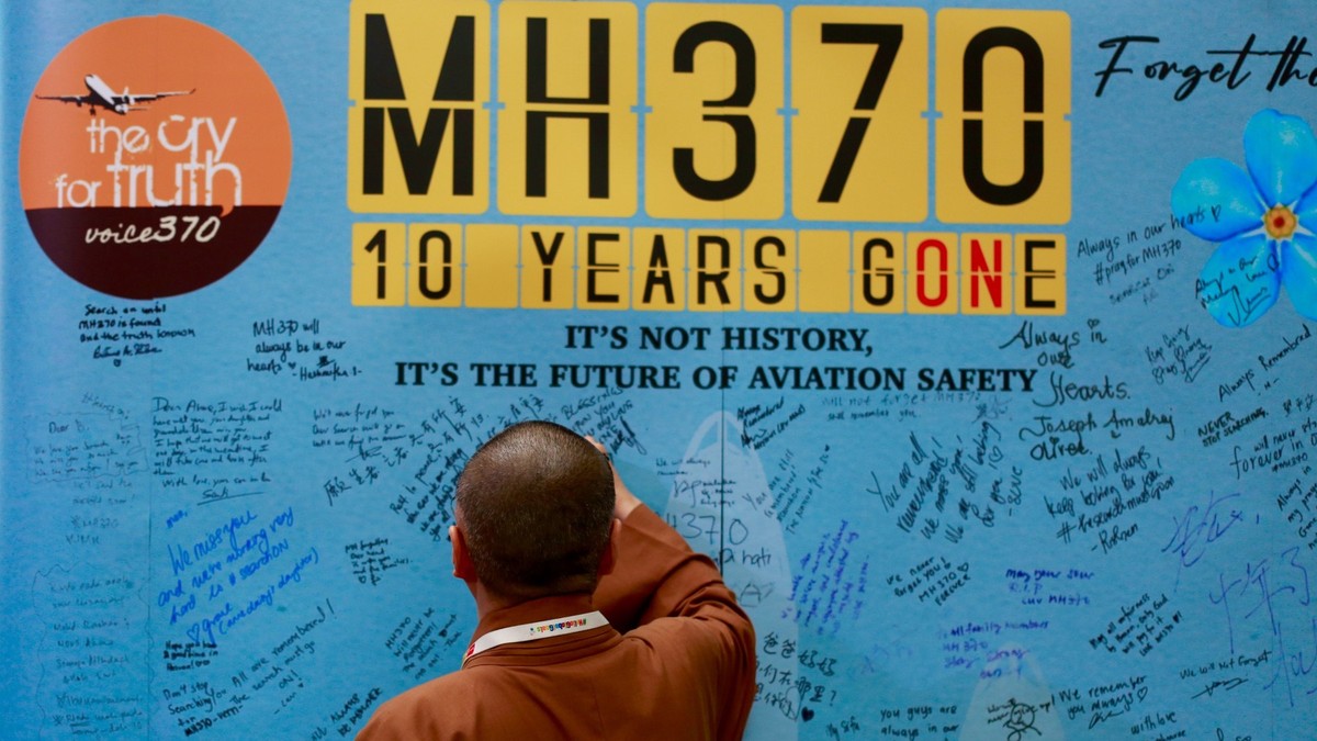 Om care scrie un mesaj pe un panou realizat cu ocazia Zilei de comemorare a zborului MH370- 3 martie 2024.