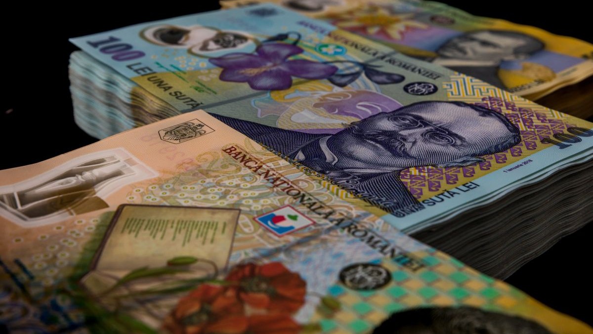 Trei teancuri de bani în bancnote de lei românești din cupiura de 50, 100 și 200 de lei, pe fundal negru