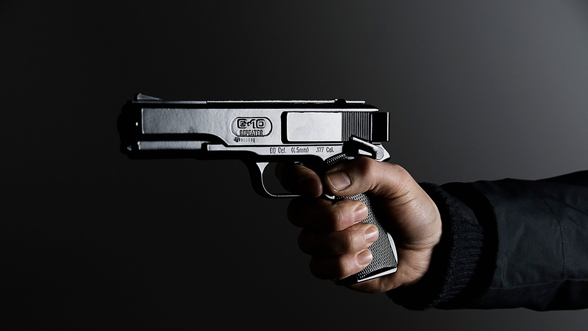 Bărbat care ține în mână un pistol.