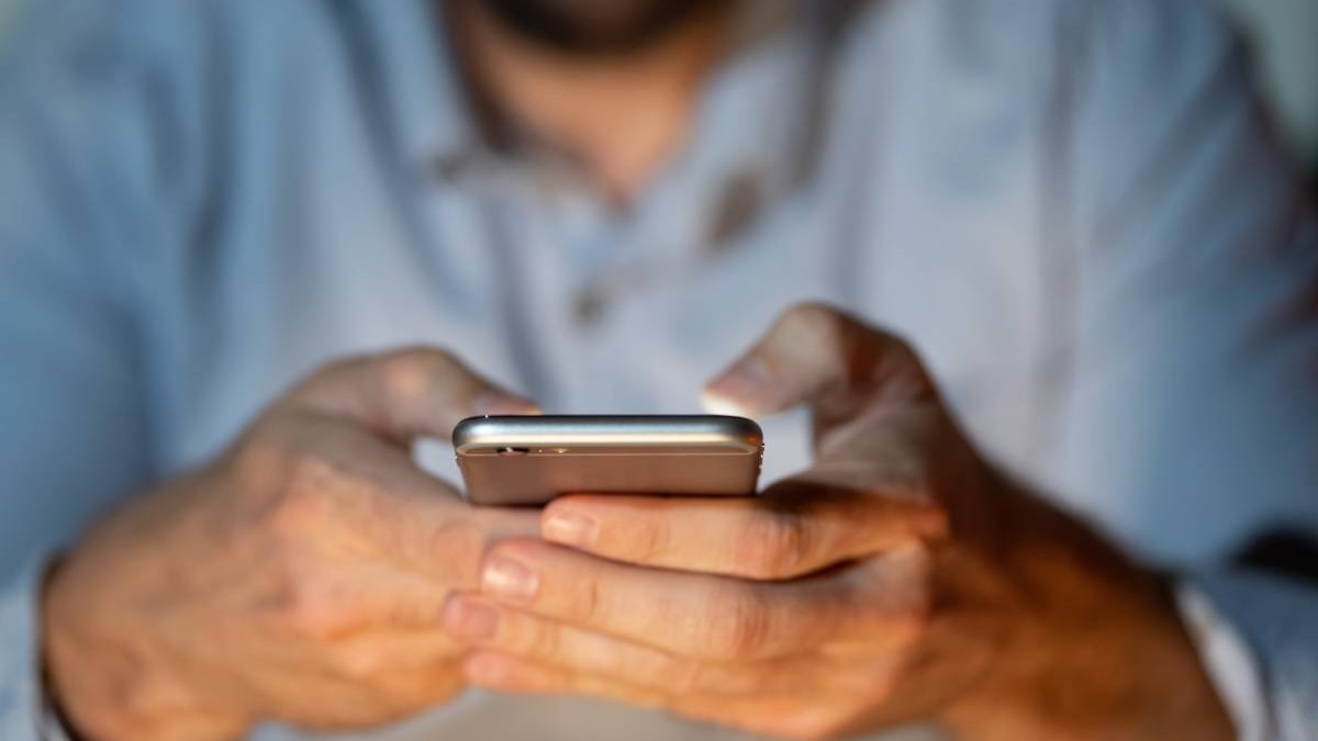 barbat intr-o camasa albastra care tine un telefon in mana