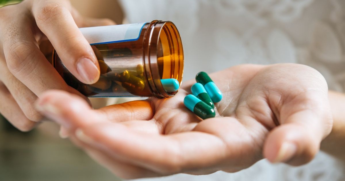 o femeie care toarnă pastilele în palmă dintr-o sticlă cu medicamente