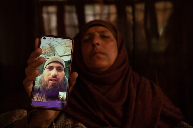 February 28, 2024, Srinagar, Jammu And Kashmir, India: The mother of Azad Yousuf Kumar, holds a cellphone displaying photos of her son wearing military uniform. Two Kashmiri men Azad Yousuf Kumar 31-years old, and Zahoor Ahmad Sheikh 30-years old, who were lured to Dubai on the promise of jobs and then deceitfully dispatched to Russia by fraudulent recruitment agencies and ordered to fight as mercenaries for Russia on the border with Ukraine. A Kashmiri family learned that their son, Azad Yousuf, had been injured in the Russia-Ukraine conflict, and said he was forced to fight on frontlines and urged the Indian government to intervene. Indian nationals were duped by the agents into fighting for Russian forces, according to the Indian publication 'The Hindu'. The families of the men have now petitioned the federal government to return them home.,Image: 851744794, License: Rights-managed, Restrictions: , Model Release: no