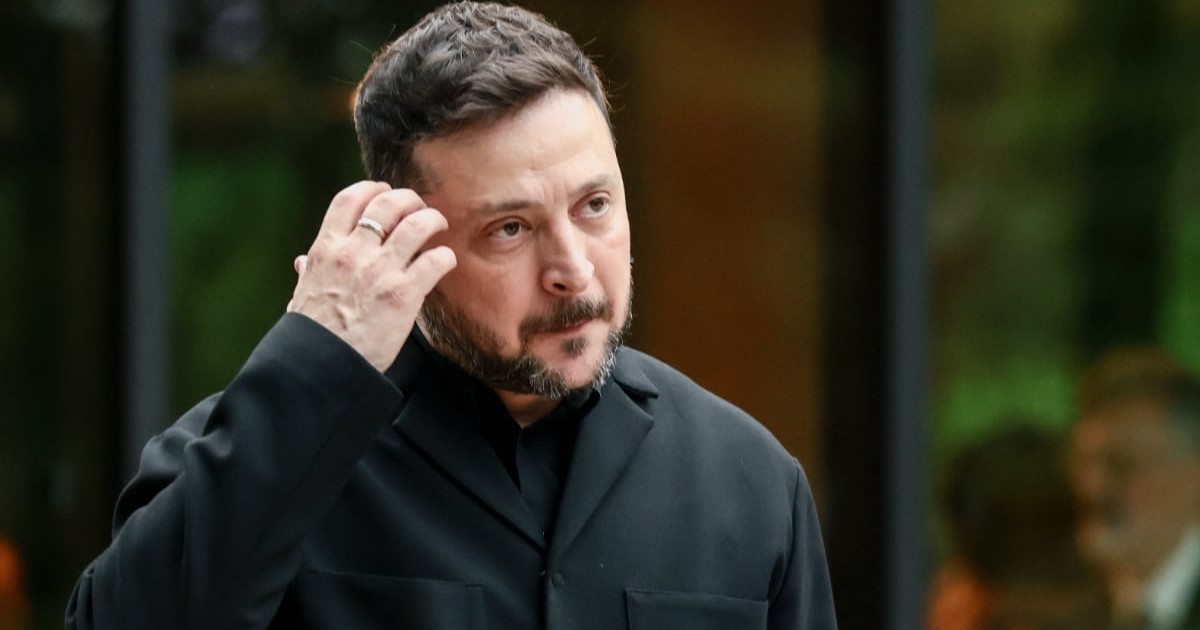 Președintele ucrainean Volodimir Zelenski, în timpul unui eveniment, este îmbrăcat în gru și se scarpină cu mâna la tâmplă