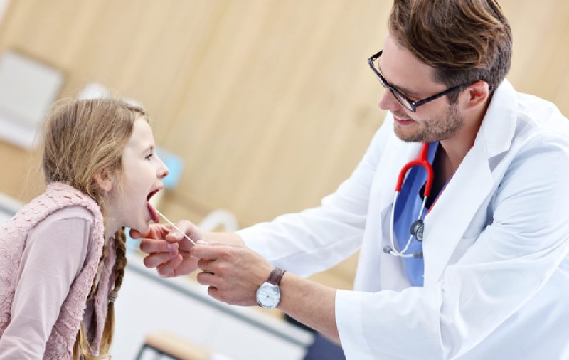 Medic  examinand un copil pentru suspiciune de streptococ beta hemolitic 