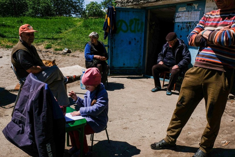 La intrarea unui buncăr, un copil care desenează folosind un scaun ca birou. Lysychansk, regiunea Luhansk. Foto: Profimedia