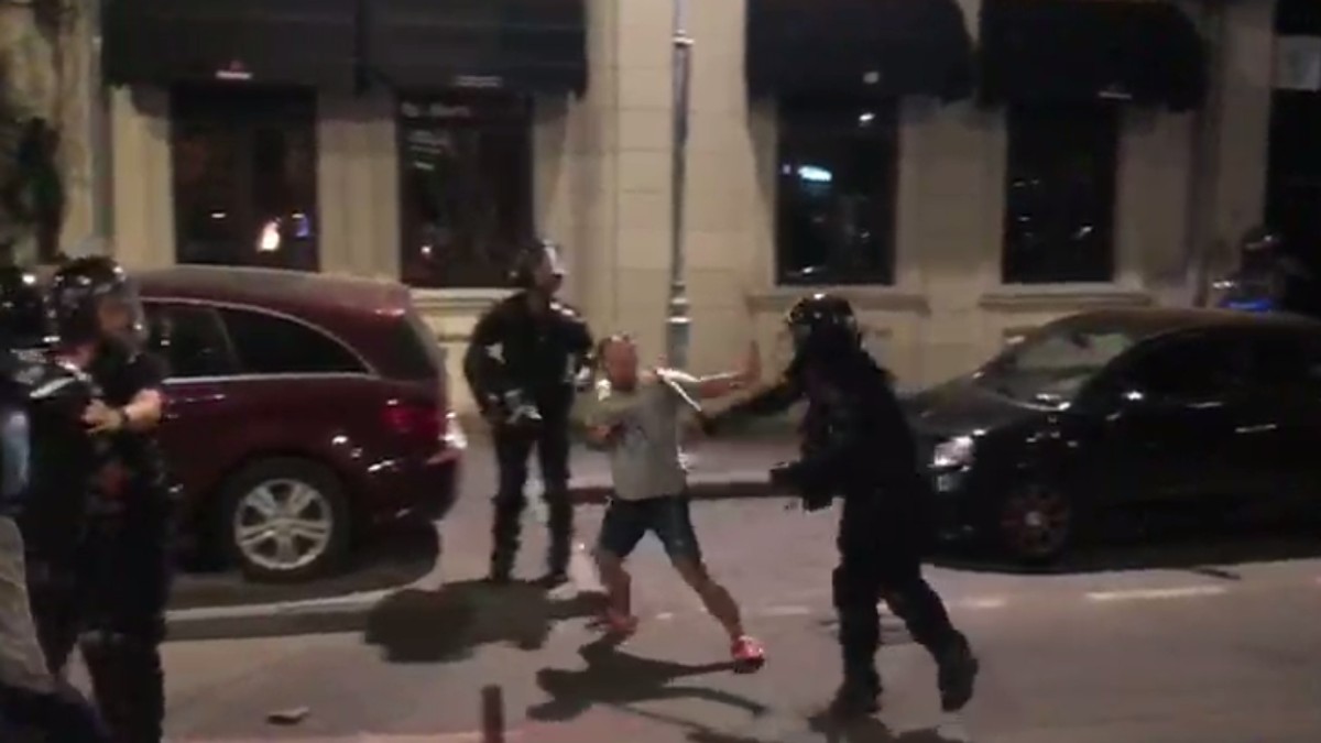 Un protestatar care mergea, cu mâinile ridicate, pe o stradă din apropierea Pieței Victoria este bătut cu bastonul de un jandarm, care îl lovește pe spate și în cap, apoi un alt jandar dă cu piciorul îl el.