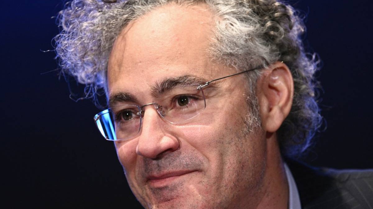 Prim-plan cu Alex Karp, CEO al Palantir, în fața unui fundal negru.