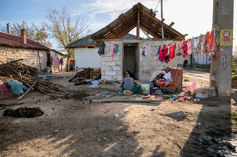 O mamă din comunitate spală rufele copiilor într-un lighean