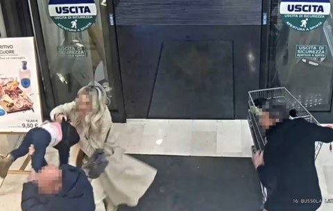 Imaginea, surprinsă de o cameră de supraveghere la ieșirea dintr-un magazin, arată un bărbat care ridică brusc un copil mic, în timp ce o femeie intervine imediat pentru a-l opri.