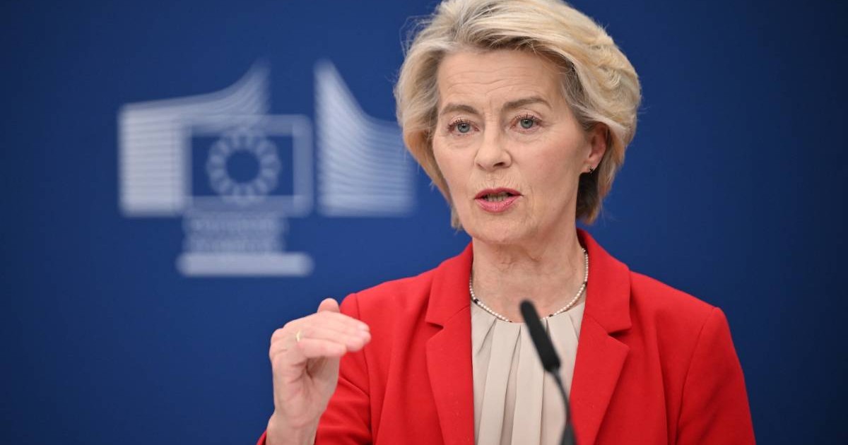 Președinta Comisiei Europene Ursula von der Leyen în timpul unei conferințe de presă, gesticulează cu mâna dreaptă și poartă un sacou roșu.