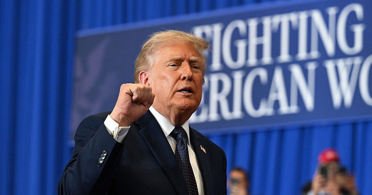 Donald Trump, îmbărcat în sacou negru, cămașă albă și cu cravată bleumarin, ridică pumnul drept în sus în semn de a transmite putere la un eveniment „Fight America” Foto: Getty Images