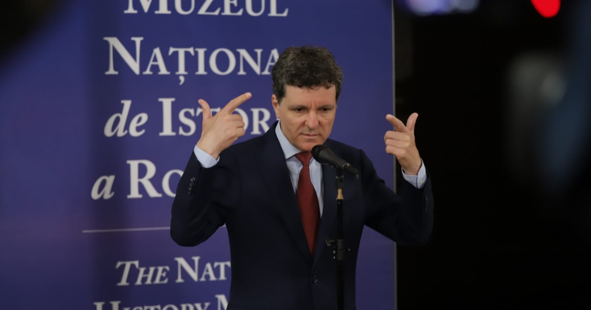 Președintele Nicușor Dan, în timpul unei conferințe de presă susținută la Muzeul de Istorie, gesticulează și le explică ceva jurnaliștilor, vorbind la microfon