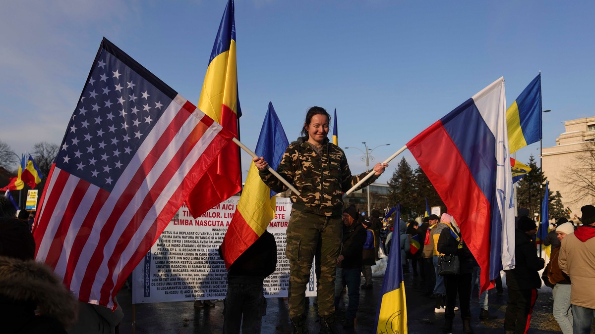Protestatară îmbrăcată în militar de la protestul pro-Călin Georgescu, cu două steaguri, al Rusiei și al Statelor Unite, 21 februarie.