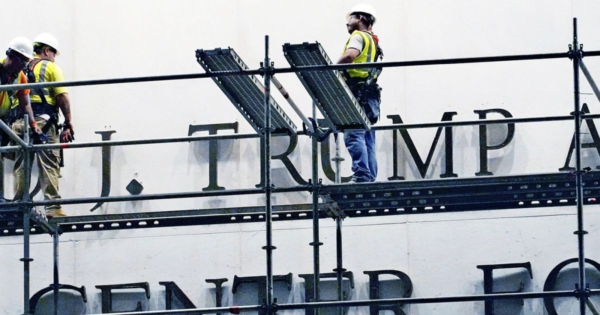 Muncitorii îndepărtează semnul cu numele președintelui american Donald Trump de pe peretele exterior al Centrului Kennedy din Washington, D.C., Statele Unite ale Americii, pe 13 iunie 2026. O instanță federală a ordonat îndepărtarea numelui președintelui Trump de pe Centrul Kennedy, hotărând că redenumirea acestuia în „Centrul Trump-Kennedy” a fost ilegală.