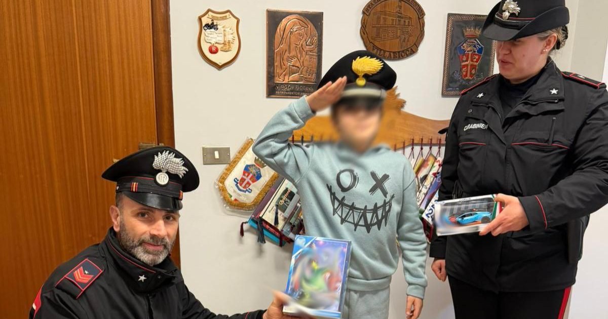 Doi carabinieri din Napoli, îmbrăcați în uniformă, alături de un băițel de 11 ani care primește cadourile de Crăciun