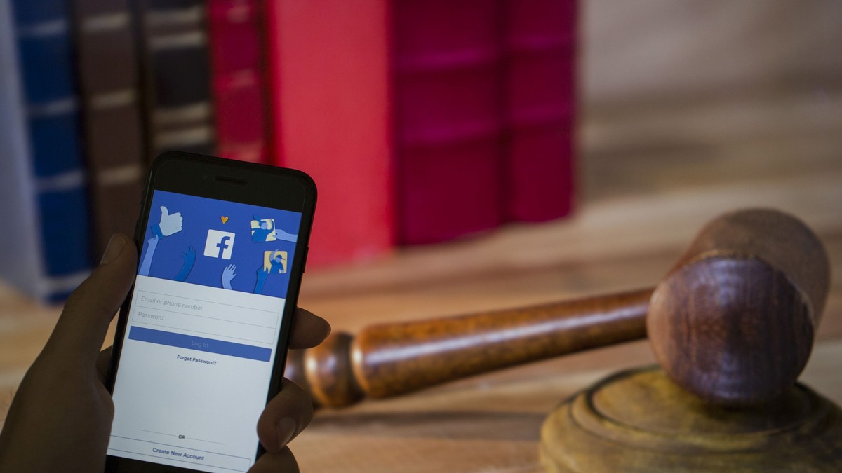 Facebook a eliminat 10.000 de aplicații suspecte, care colectau date despre utilizatori, dar nu vrea să știe lumea despre ele. Aplicația Facebook pe un smartphone și un ciocănel judecătoresc pe fundal